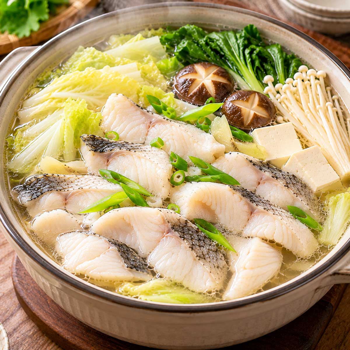 清湯中盛有熟魚片、豆腐、蔬菜與菇類的魚片火鍋